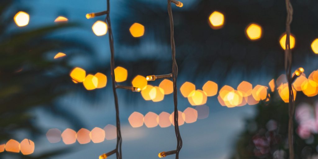 blurred light bokeh with coconut palm tree background on sunset blurred light bokeh with coconut palm tree background on sunset, yellow string lights with bokeh decor in outdoor restaurant.